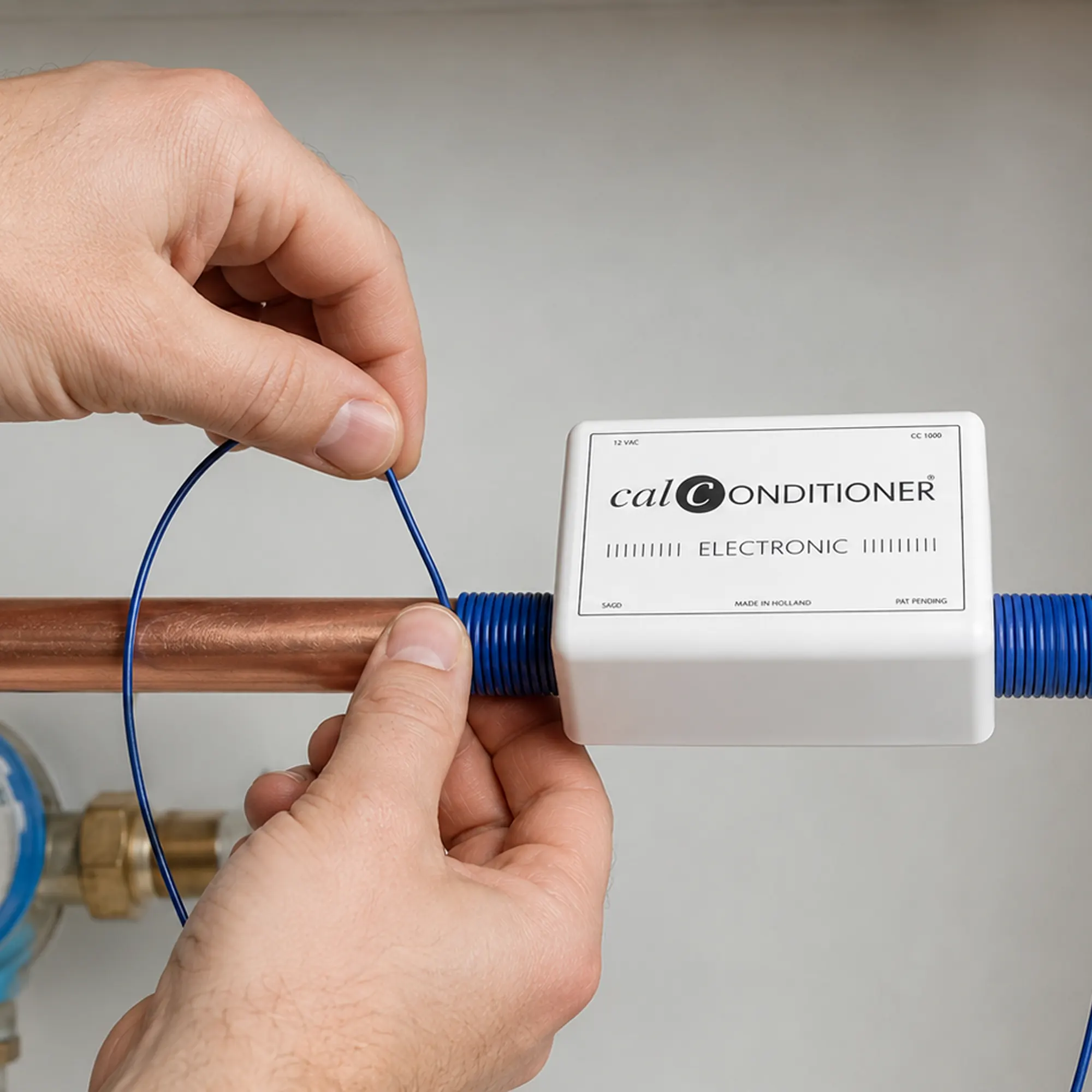 Avvolgimento del cavo blu del Calconditioner intorno a un tubo dell’acqua